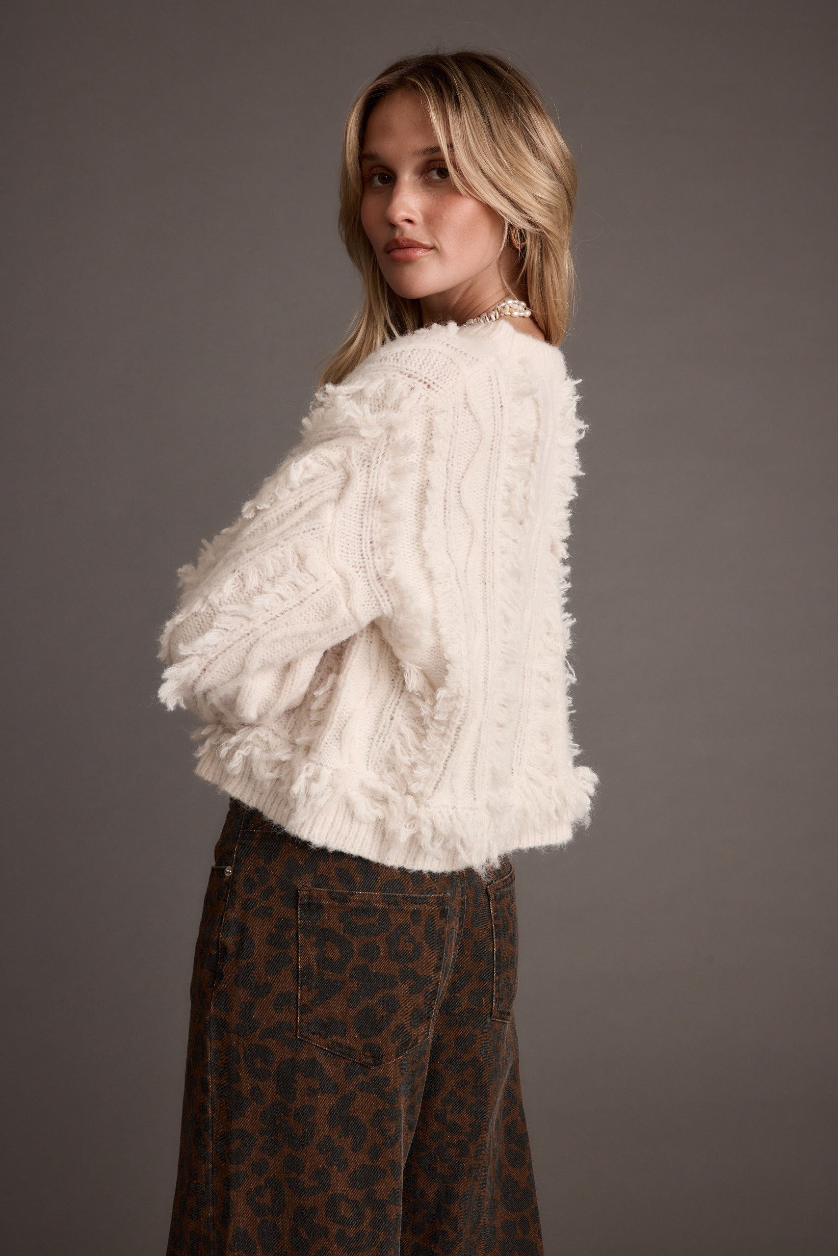 Detail shot of the Lorie Beige Fringe Sweater highlighting the fringe elements.