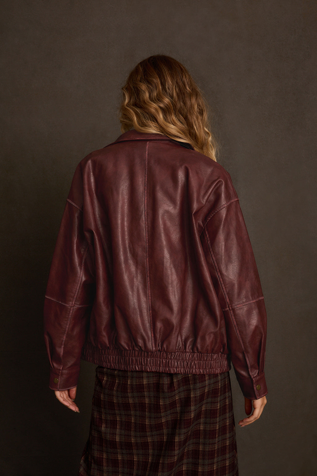 Oversized jacket outdoor shot layered over sheer mesh top with denim and belt