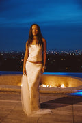 Model wearing the 12th Tribe Julia White Beaded Maxi Skirt set with the matching Luci White Beaded Tank, featuring intricate beadwork and a flowing, floor-length silhouette, styled with a cropped top and strappy heels for weddings, cocktail parties, and evening events