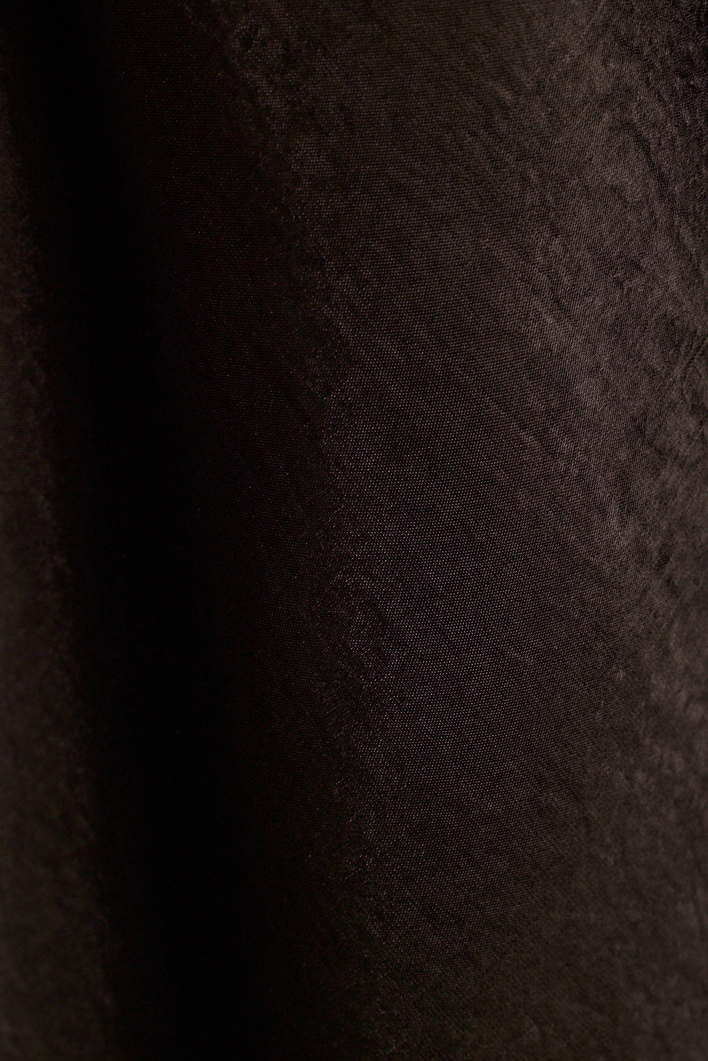 Close-up of black satin fabric with soft draped folds.