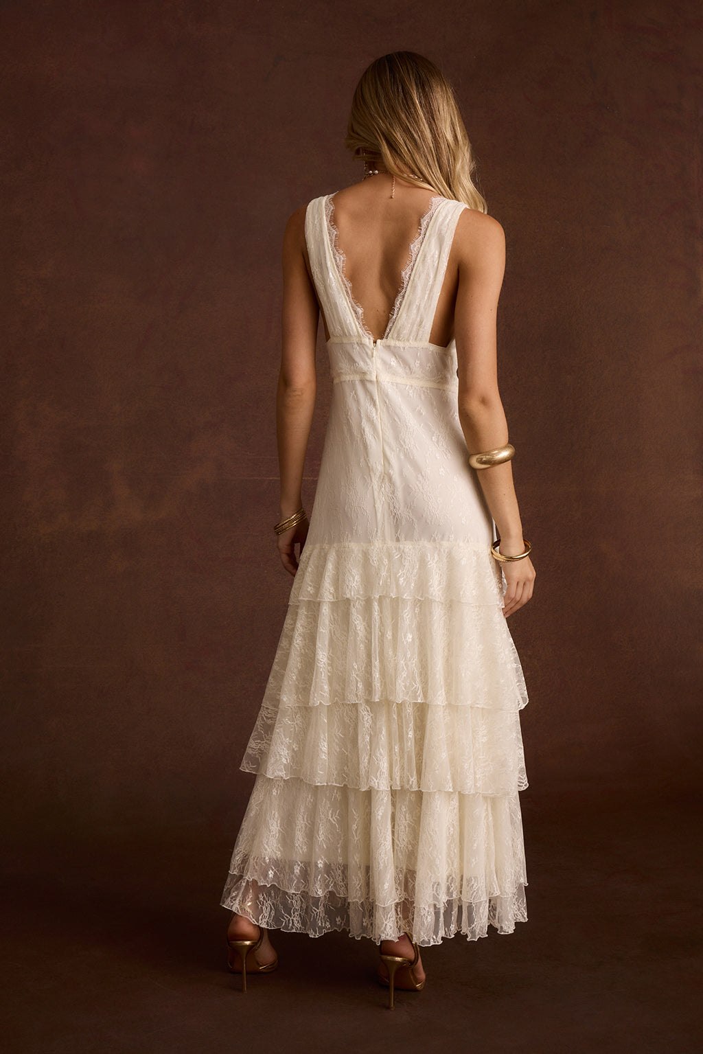 Back view of cream lace maxi dress with V-back and tiered ruffle skirt.