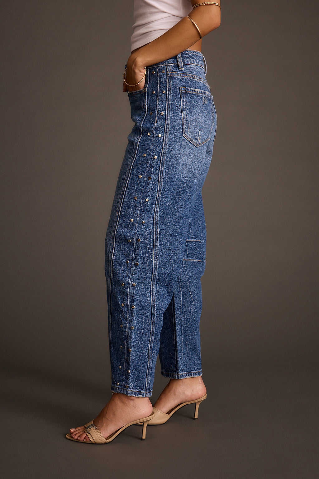 Women's studded barrel jeans with silver studs down the seam, side profile view