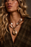 Gold pendant necklace with layered beaded chains and hammered teardrop pendant, close-up on model