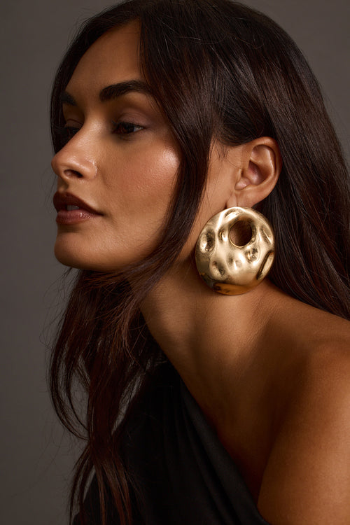 Model wearing gold statement earrings, side profile portrait