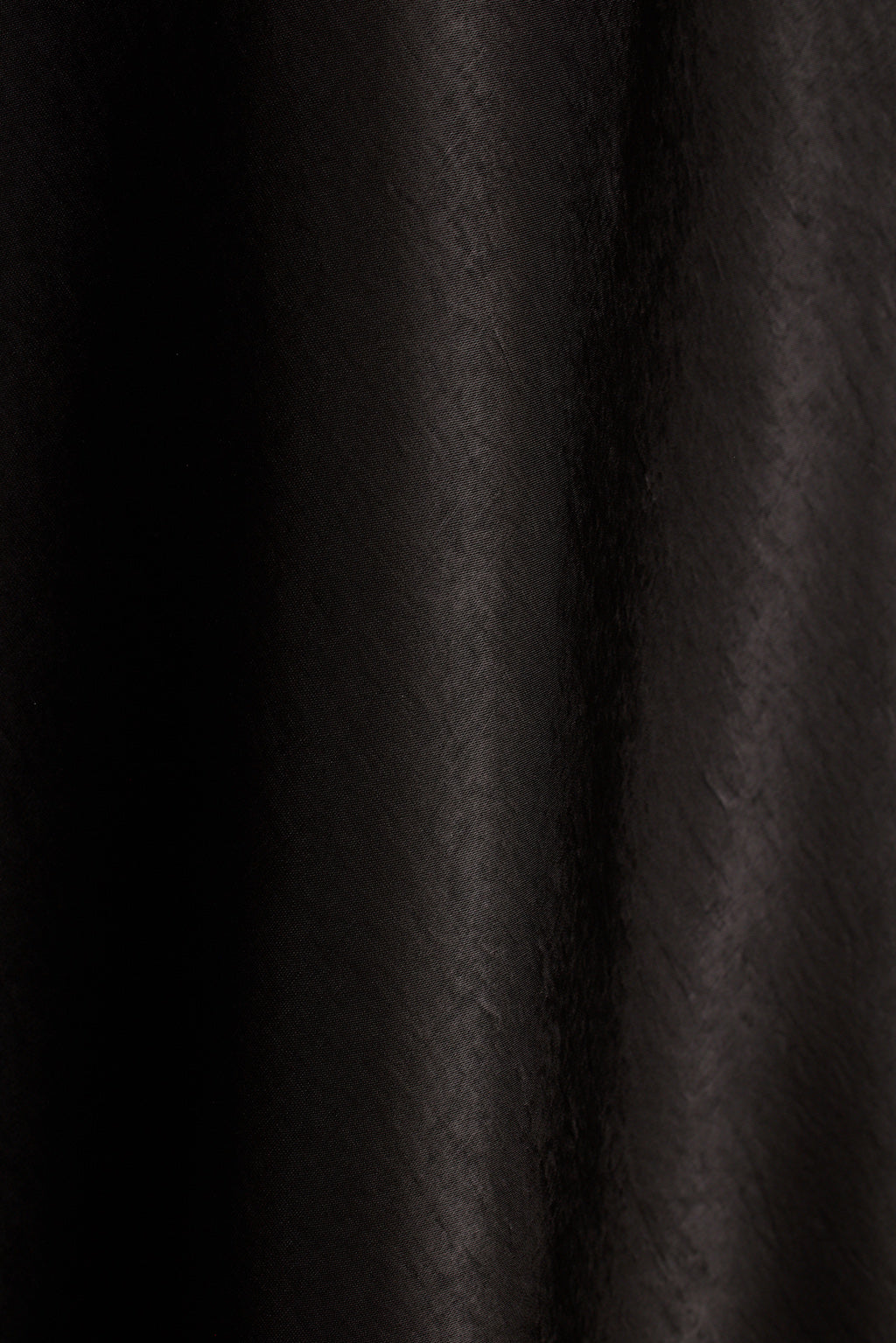 Close-up of black satin fabric with soft draped folds.