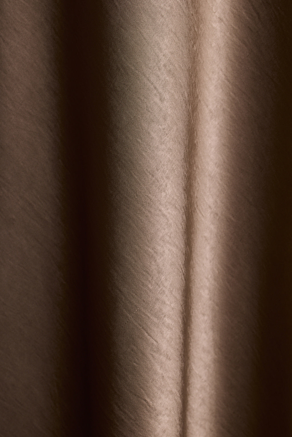 Close-up of brown satin fabric with soft draped folds.