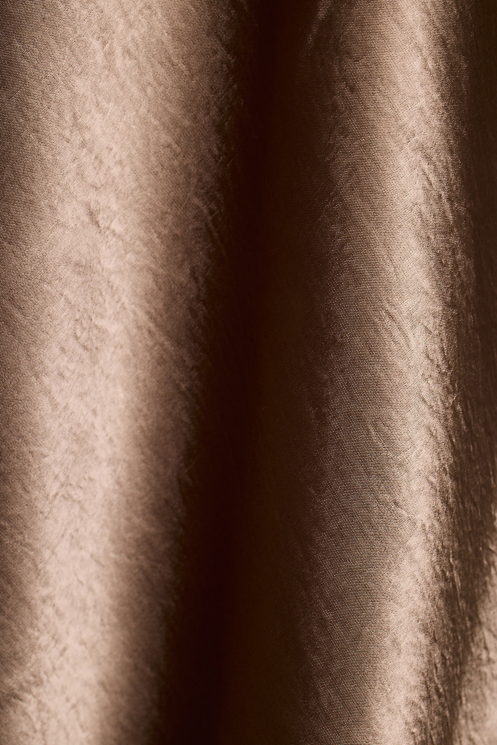 Close-up of brown satin fabric with soft draped folds.
