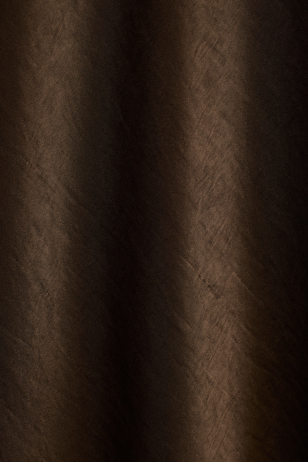 Close-up of dark bronze satin fabric with soft draped folds.