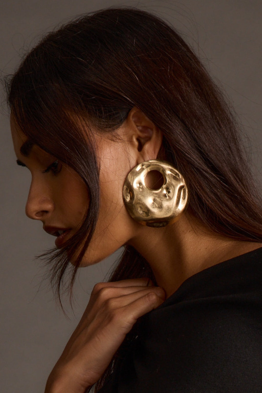 Side profile close-up of a woman wearing a chunky organic-shaped gold earring