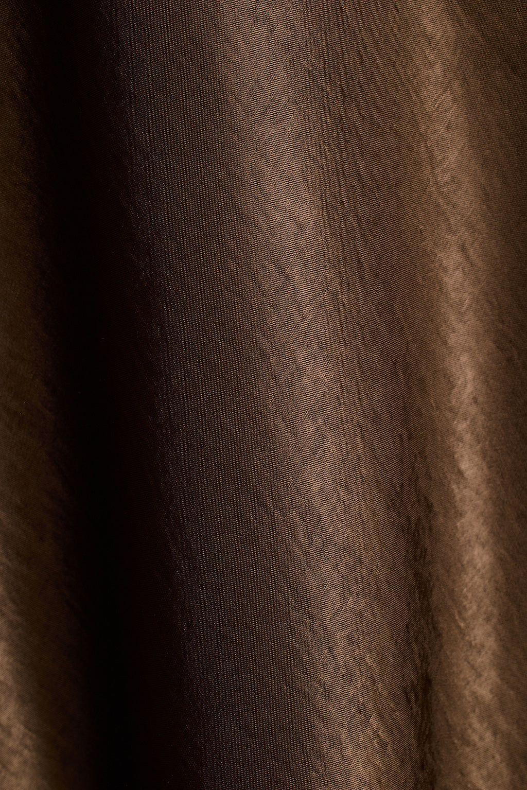 Close-up of brown satin fabric with soft draped folds.