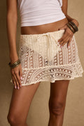 Model wearing the 12th Tribe Prairie Wind Natural Crochet Mini Skirt, a natural crochet knit mini featuring a drawstring waist with front tie closure, slip-on style, and ruffle detail at the sweep, perfect for summer soirées, festival-ready looks, and stylish warm-weather outfits
