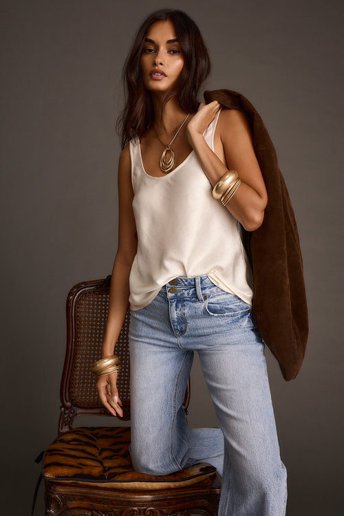Women's ivory satin tank top styled with light-wash jeans and a faux-fur jacket