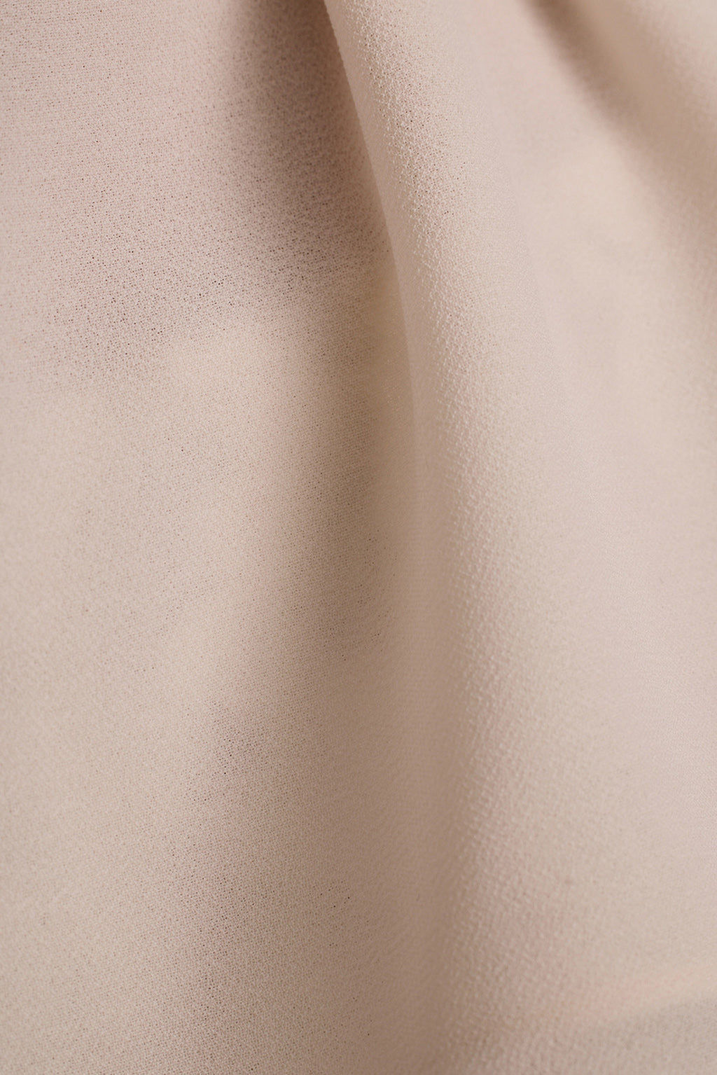 Close-up of beige crepe fabric with soft draped folds.