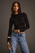 Woman wearing a black off-the-shoulder top with wide-leg jeans and stacked gold bangles