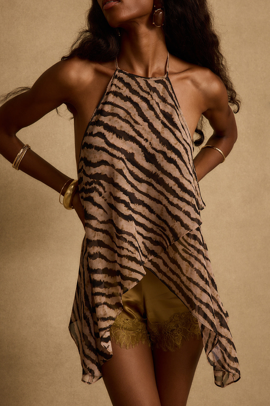Model wearing the 12th Tribe Rayna Tiger Stripe Halter Top, a lightweight sheer layered chiffon halter top featuring a bold tiger stripe print, high neck, and an adjustable behind-the-neck tie back detail. Perfect for tropical vacation outfits, summer festival looks, and warm weather nights out.