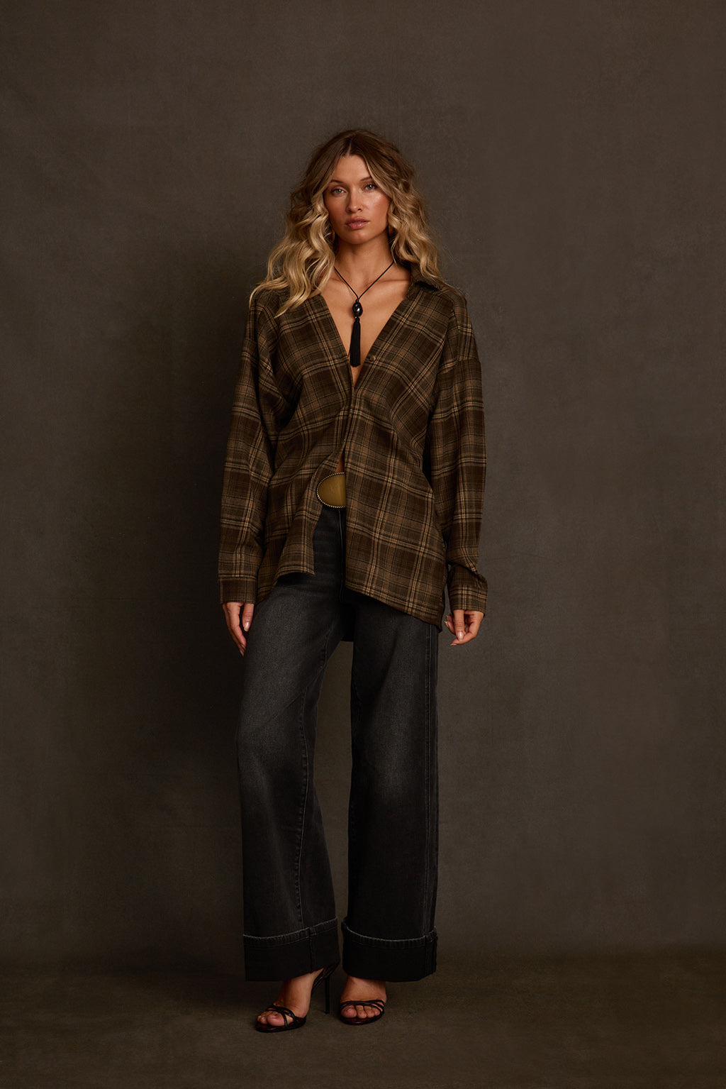 Flannel top outdoor full body shot with barrel jeans, pointed boots, and fringe bag
