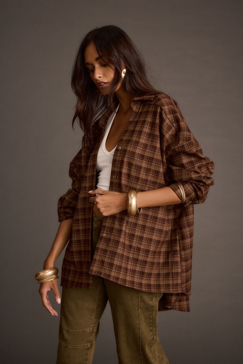 Mocha plaid flannel shirt worn open over a white tank top and olive pants, styled with gold bracelets
