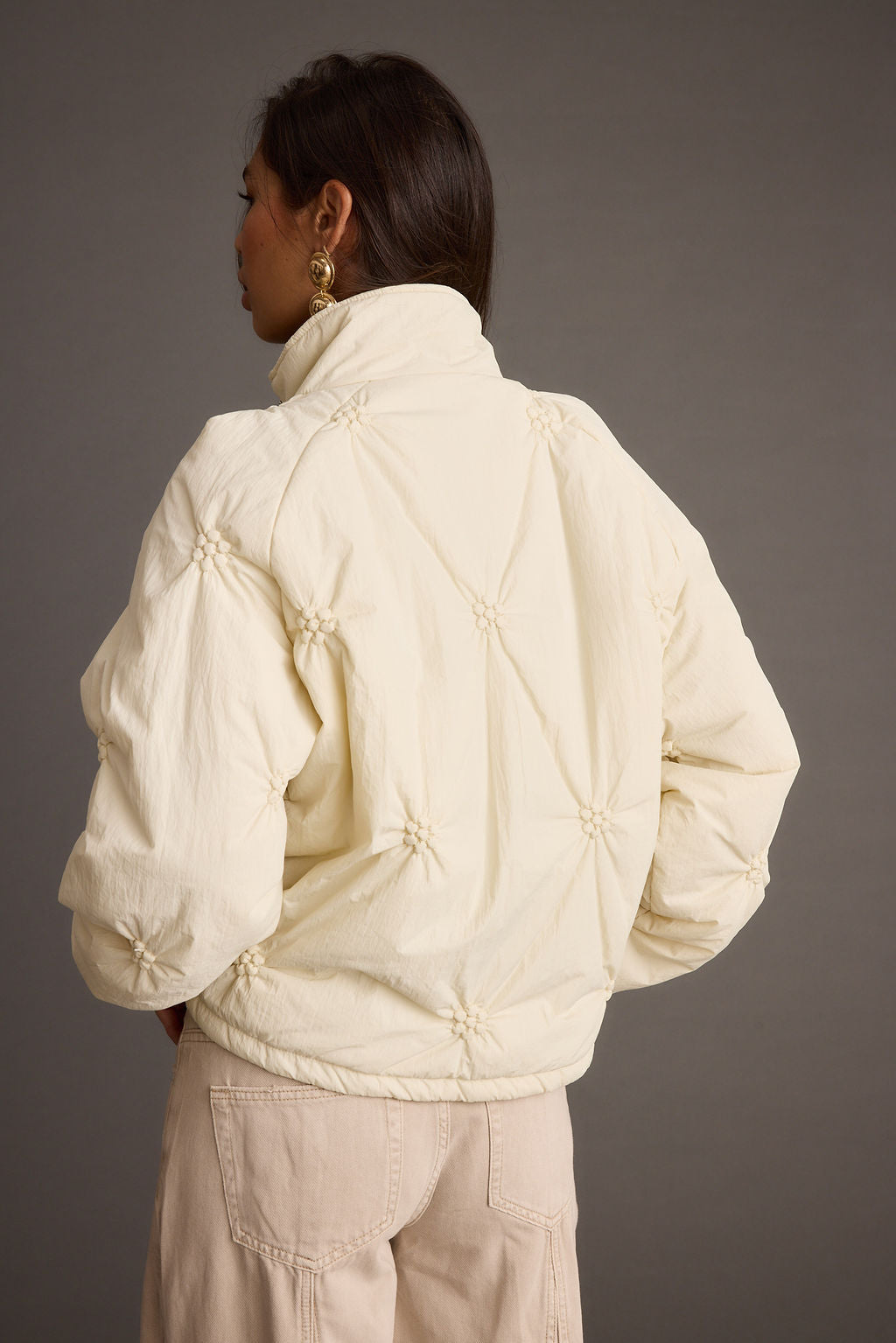 Full-length view of the cream jacket showing the drape and movement.
