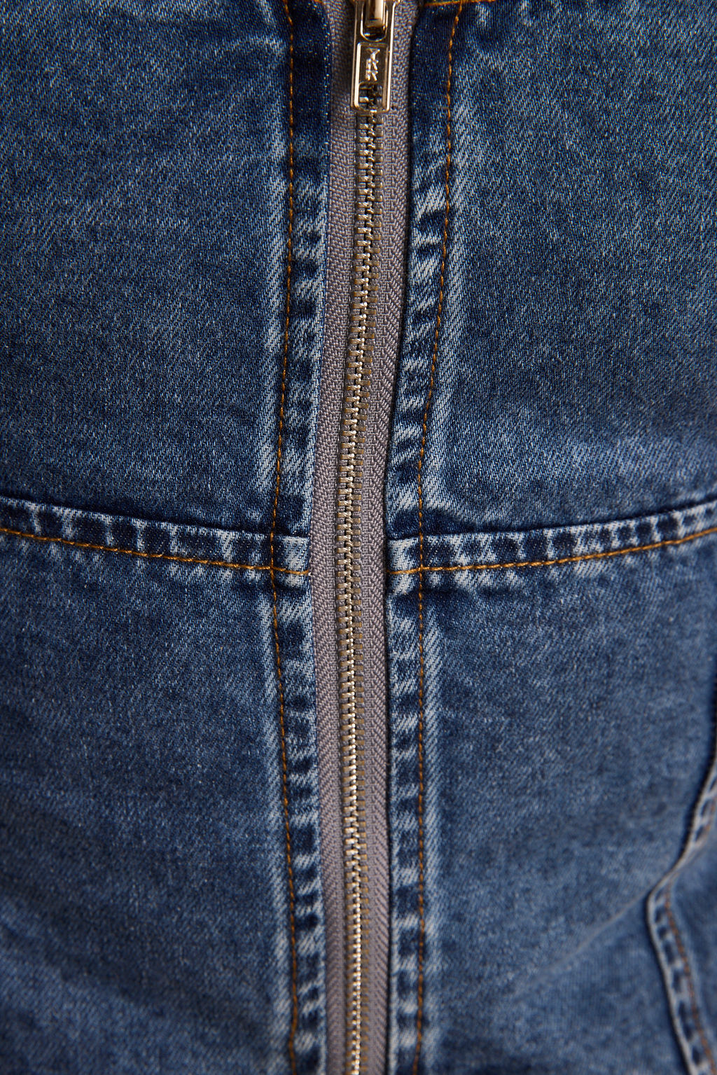 Close-up of blue denim corset back with center silver zipper and stitched seam details