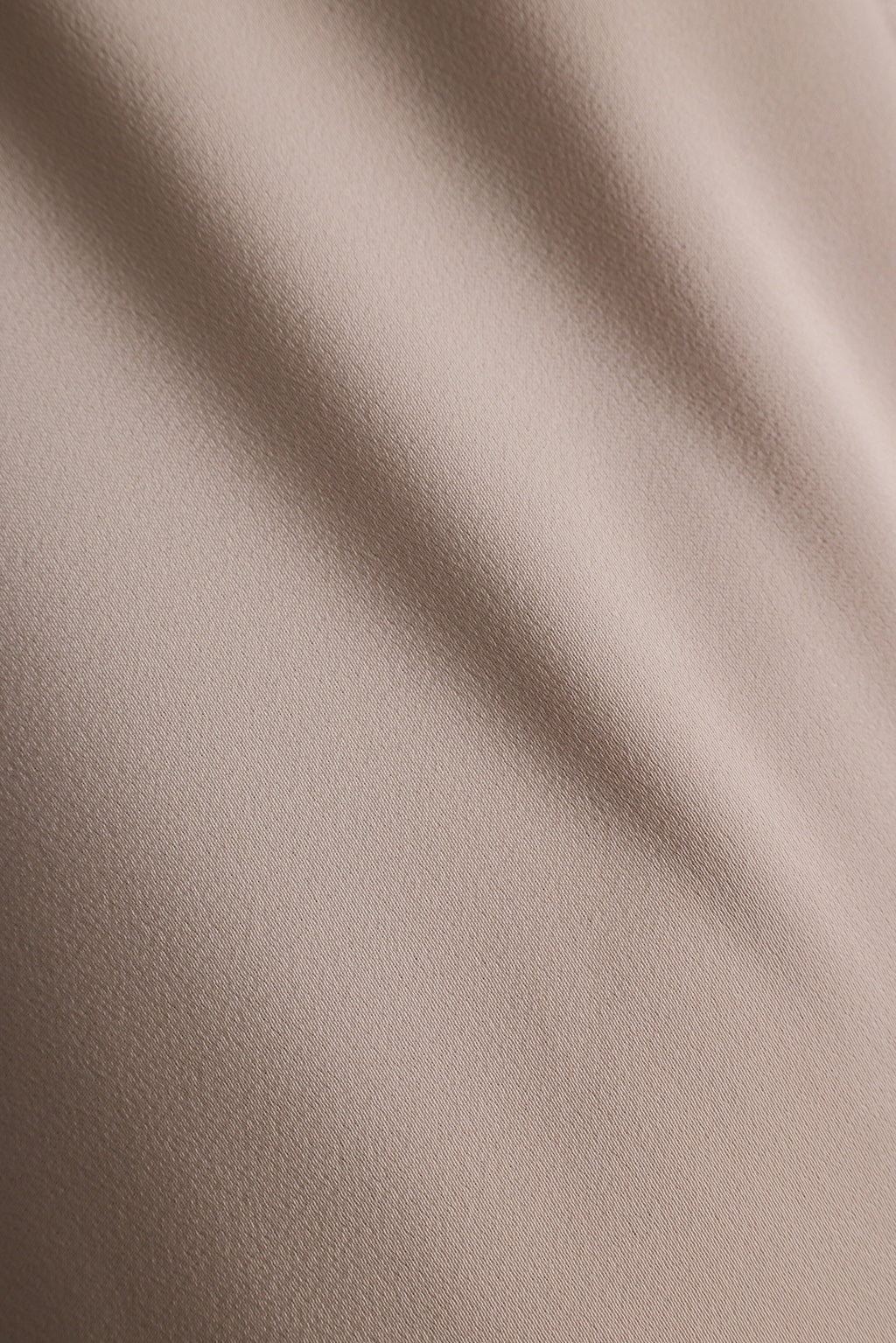 Close up of taupe satin fabric with soft, flowing folds.