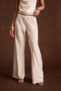 Ivory cowl neck satin top styled with matching wide-leg satin pants and layered gold bracelets.