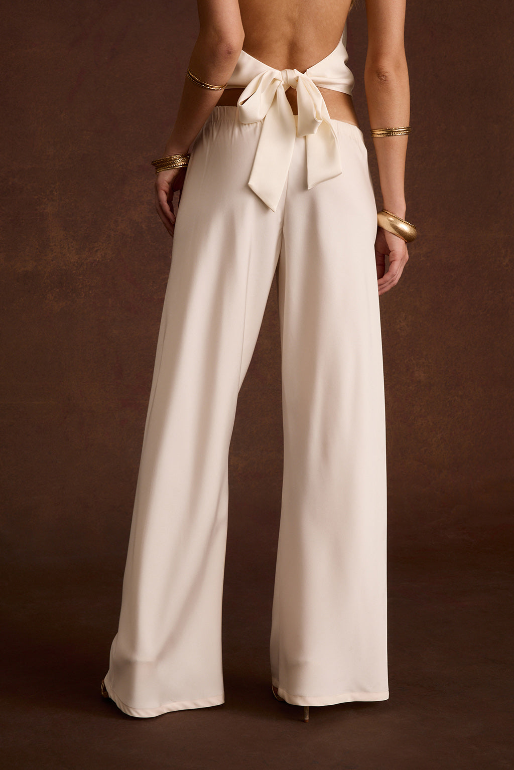 Ivory satin top with a tie-back bow detail paired with matching wide-leg satin pants.