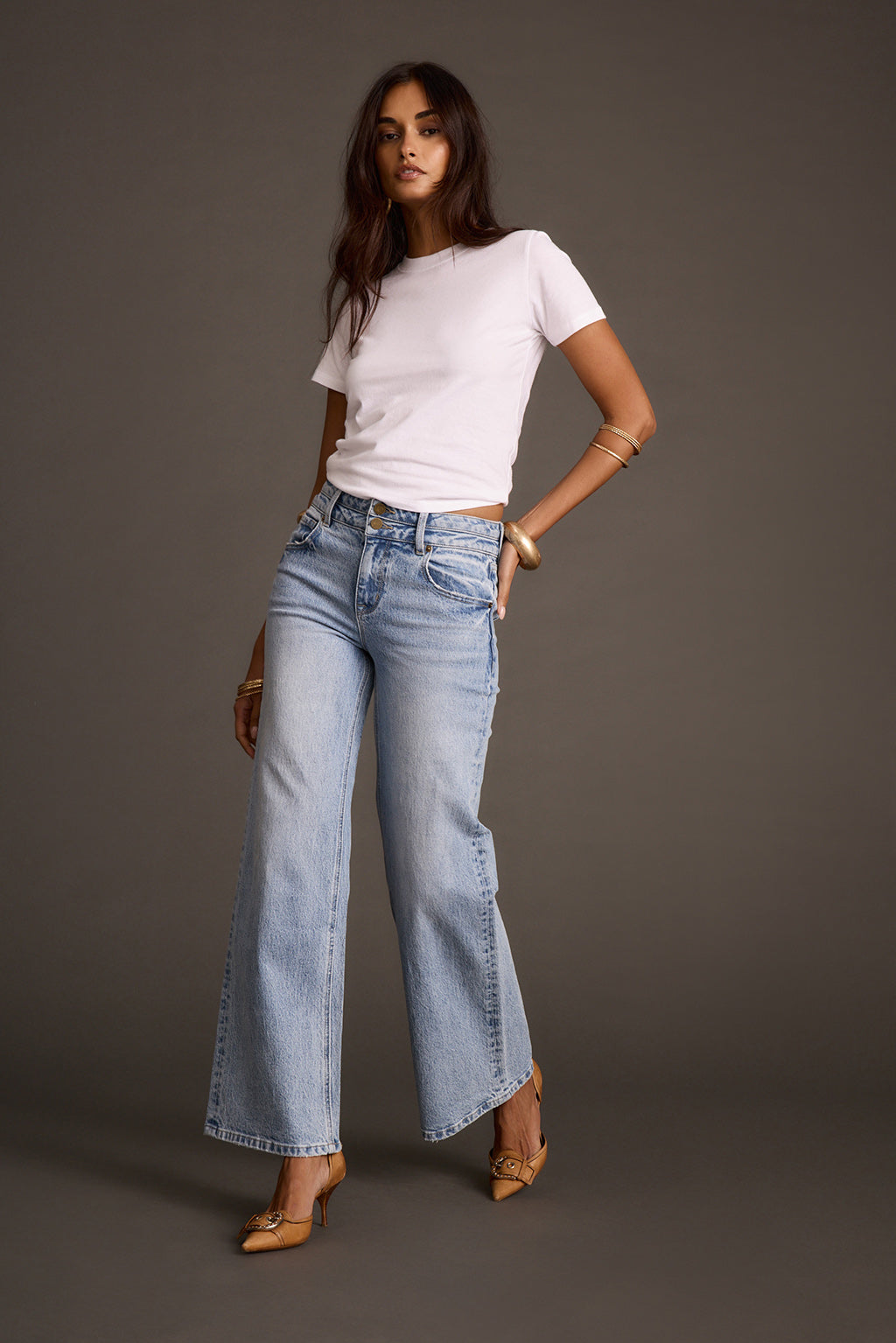 Women's light-wash flare denim jeans styled with a white t-shirt and tan heels, front view