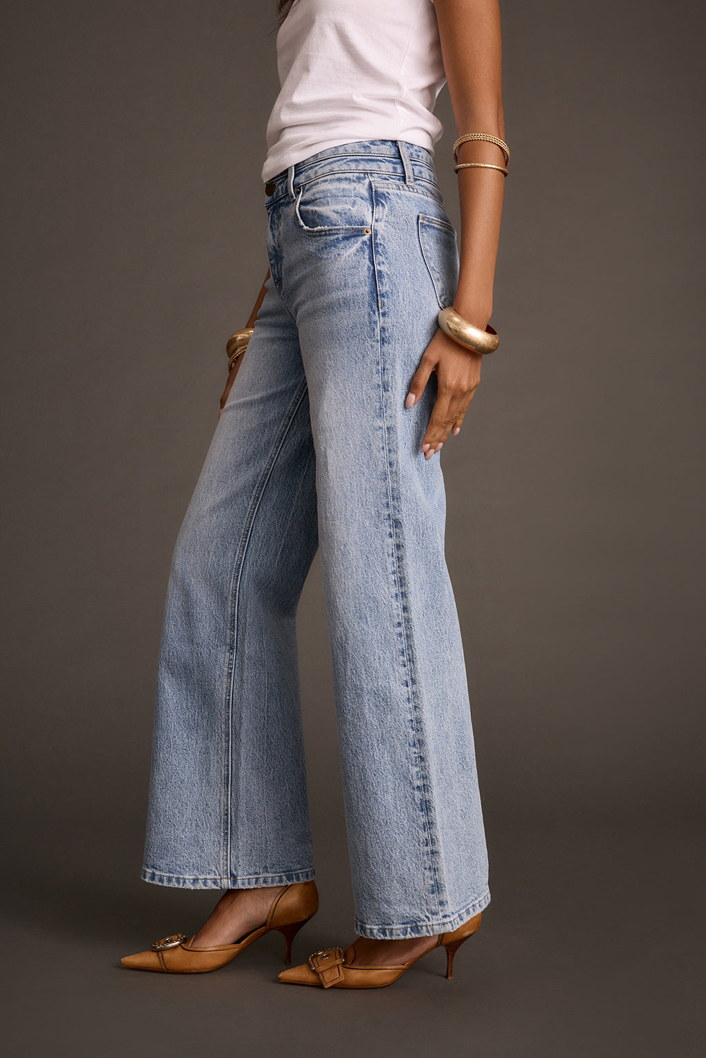Women's light-wash flare denim jeans, side view styled with brown pointed-toe heels