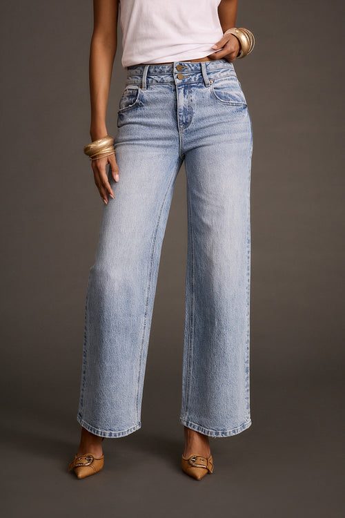 Close-up of light-wash flare denim jeans paired with gold bracelets and tan pointed-toe heels