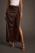 Front view of a brown satin tie maxi skirt with a thigh-high slit, paired with a white crop top and buckled sandals