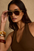 Model wearing the Sagebrush Aviator Sunglasses, featuring light green frames and brown lenses, perfect for adding a stylish, modern touch to summer outfits, beach days, and festival-ready looks