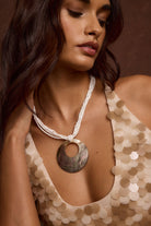 Model wearing the 12th Tribe Serena Shell Pendant Necklace with white beaded detail, featuring a delicate shell pendant, styled layered with other necklaces or solo for festivals, beach days, weddings, and casual everyday wear