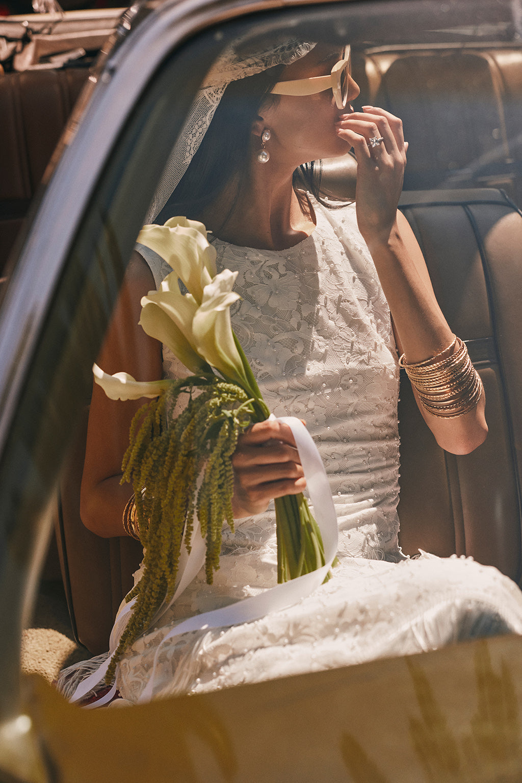 White floral lace maxi dress with a round neckline and pearl beading, shown seated.