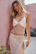 Model wearing the 12th Tribe Oceana Pearl Payette Top, a pearl and sequined mesh backless halter top featuring seashell-inspired payette detailing, adjustable neck and back ties, lined cups, and an open sheer mesh body, perfect for festival-ready looks, summer soirées, and statement evening styling