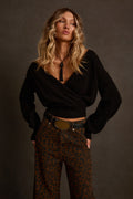 Surplice sweater in black with deep V wrap neckline, styled with leopard print jeans and oval belt