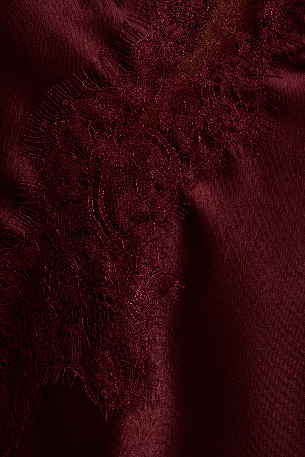 Close-up of burgundy satin fabric with delicate lace applique detailing