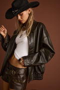 Model wearing the 12th Tribe London Calling Brown Oversized Faux Leather Jacket featuring an oversized fit and drop shoulder, perfect for adding a statement touch to everyday outfits, evening looks, and special occasions