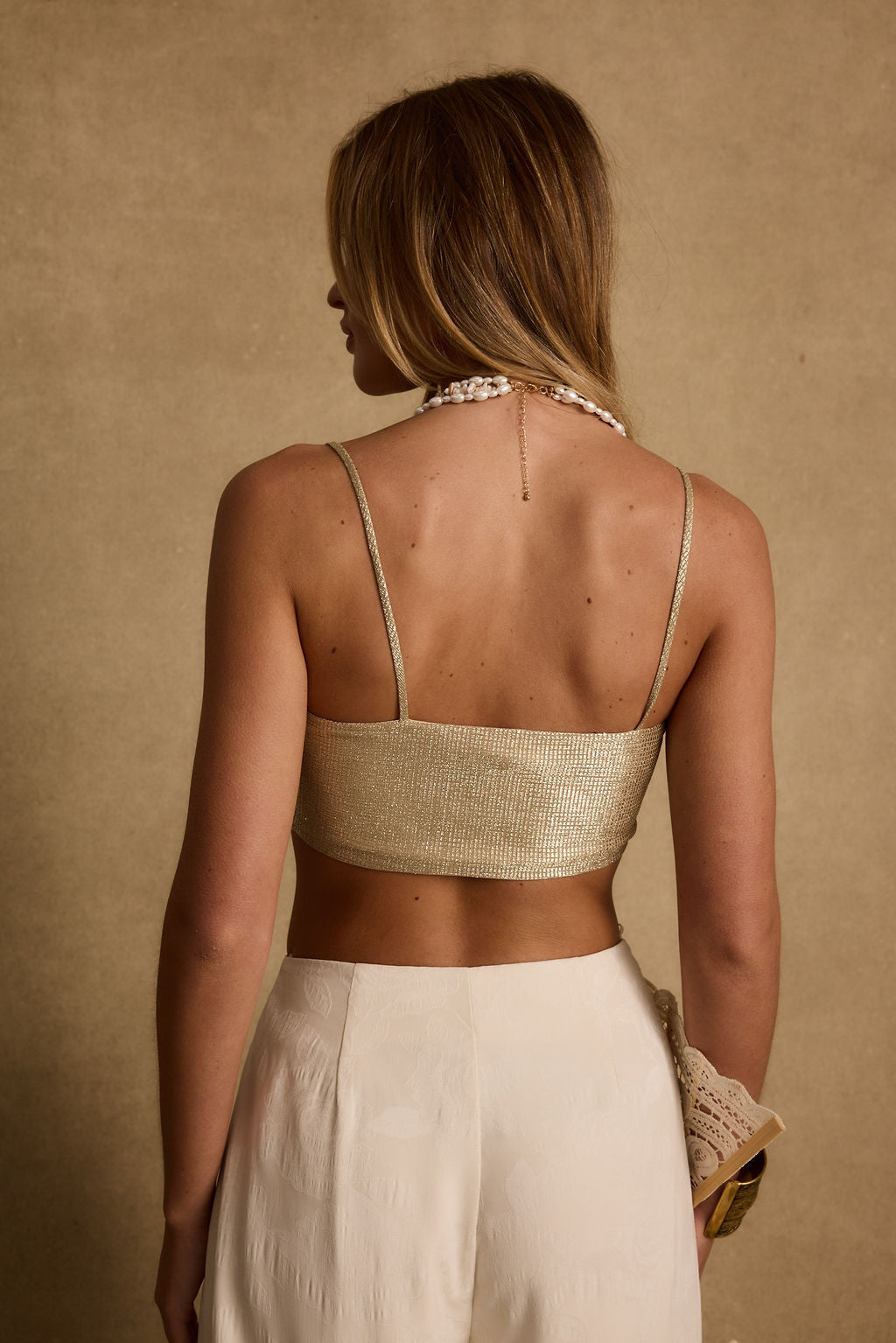 Back view of the gold metallic crop top showing the silhouette and fit.