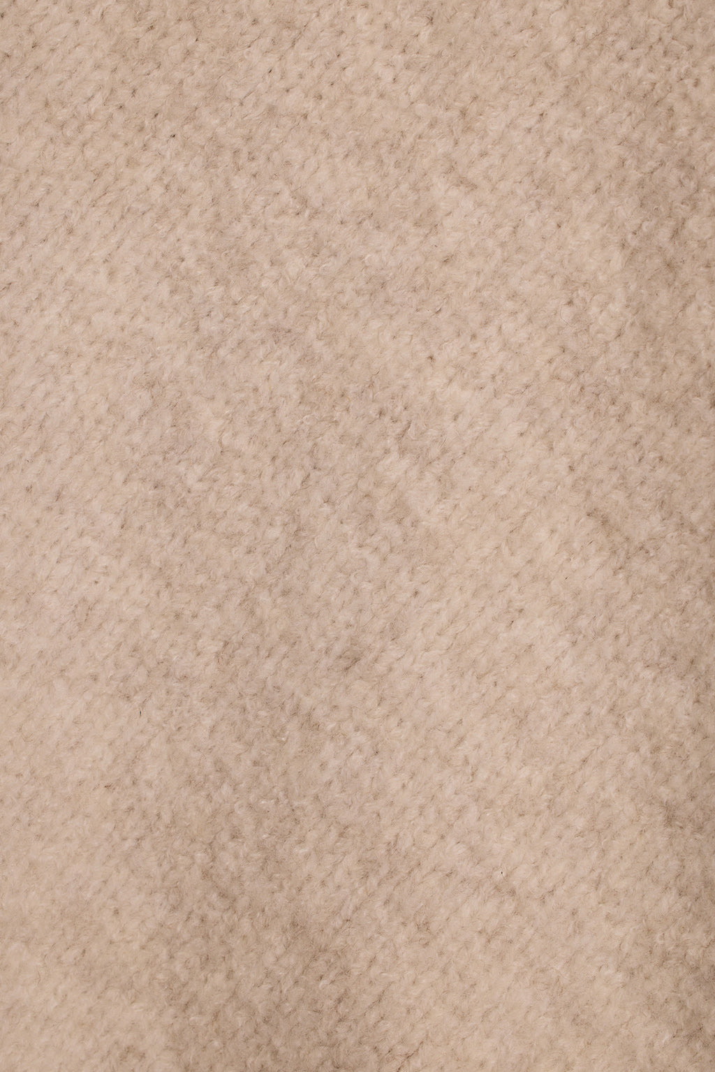 Cream knit poncho fringe detail close-up showing thick twisted yarn fringe trim