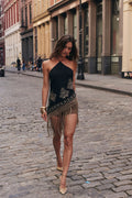 Woman walking on a cobblestone street wearing a black fringe halter top with gold embroidery