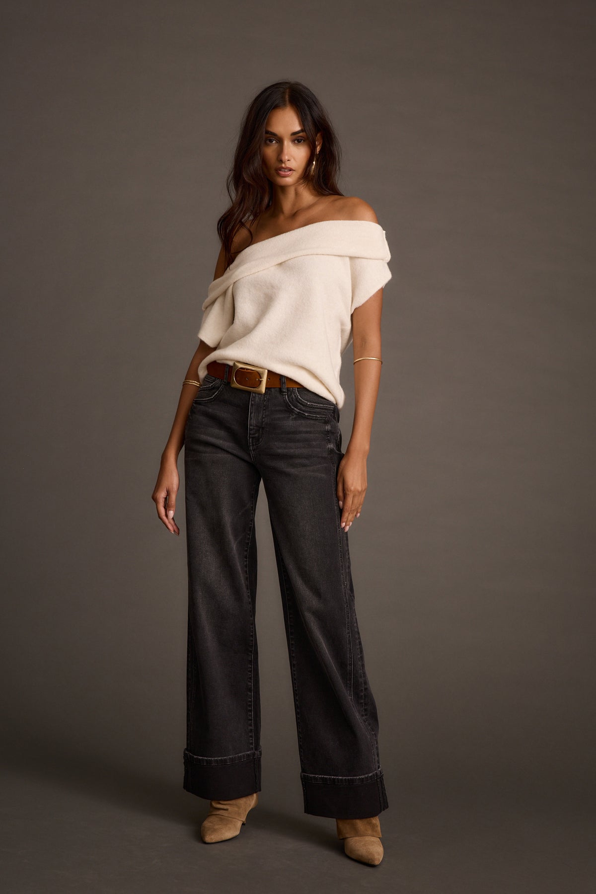 Woman wearing black wide-leg jeans with a cream off-the-shoulder sweater and tan heels