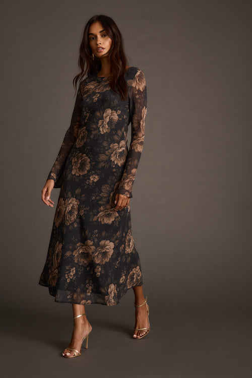 Woman modeling a sheer floral mesh dress with clear strappy heeled sandals