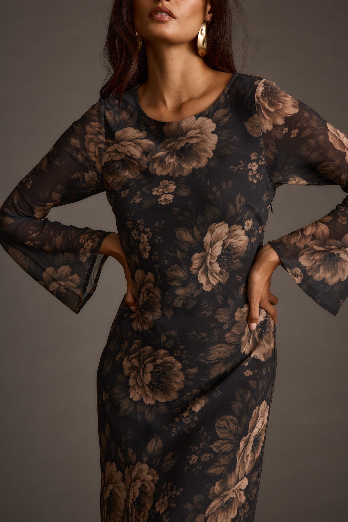 Close-up of a woman wearing a black floral chiffon maxi dress with gold hoop earrings