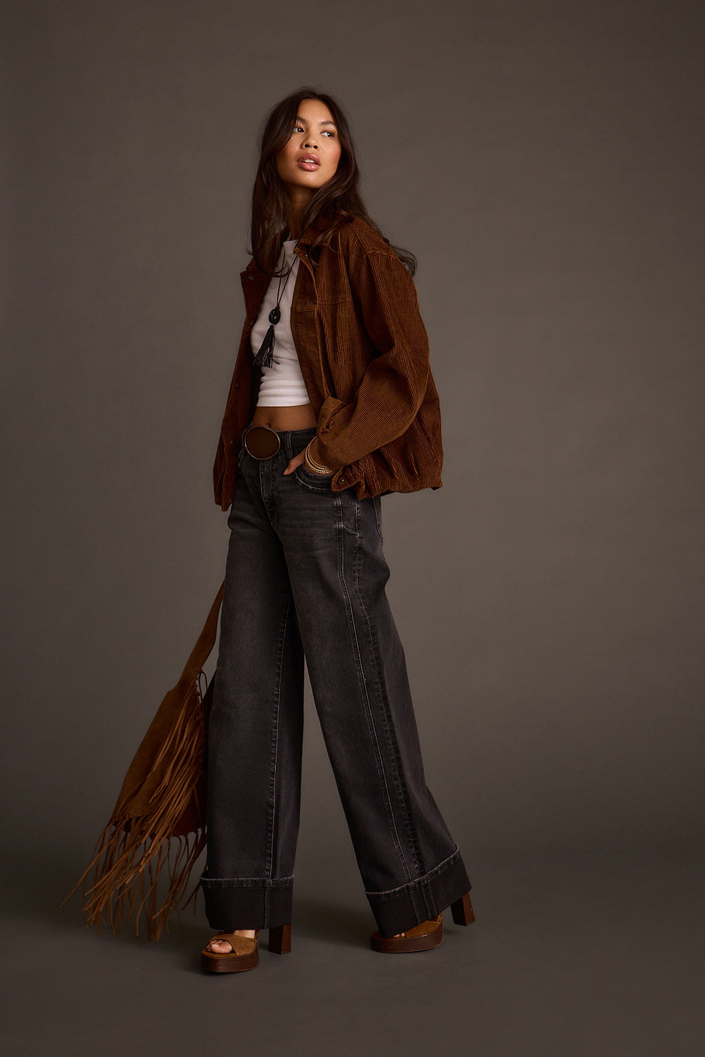 Model posing in a mocha corduroy jacket with wide-leg jeans and platform sandals