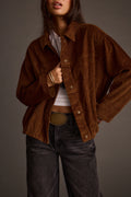 Close-up of a mocha corduroy jacket worn open over a white cropped top and gold bangles