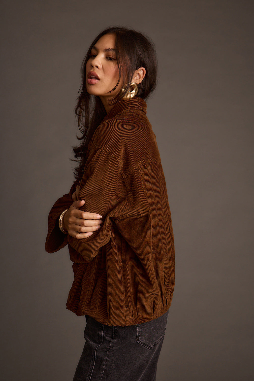Side profile of a mocha corduroy jacket paired with gold hoop earrings