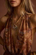 Model wearing the 12th Tribe Willa Mixed Metal Pendant Necklace, a statement necklace featuring a circular pendant with textured metal detailing, perfect for elevating festival-ready looks, summer soirées, and stylish warm-weather outfits