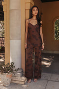 Model in espresso brown floral satin pants and matching cami by a villa column.