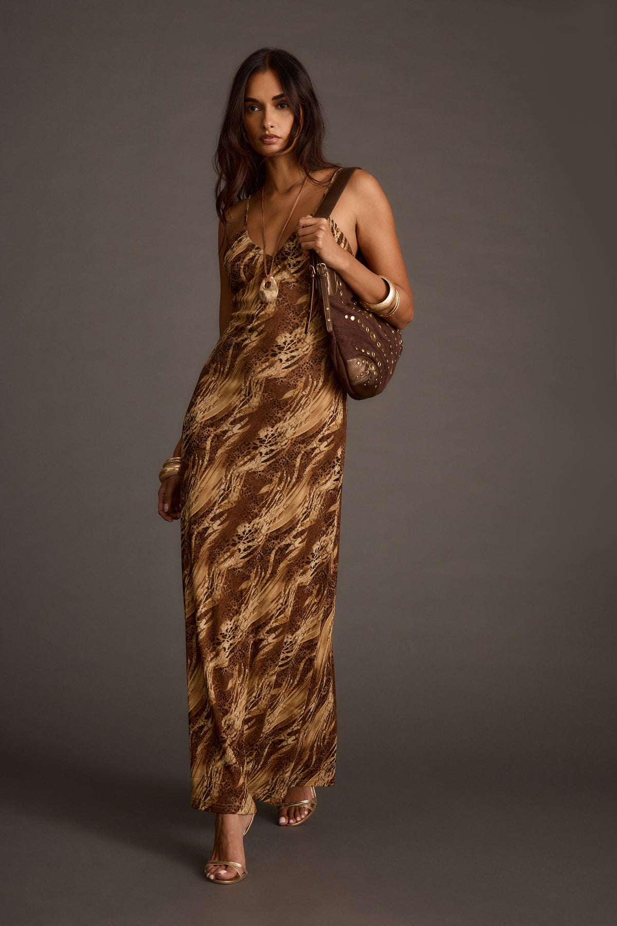 Woman modeling a brown and beige animal print maxi dress with a studded shoulder bag