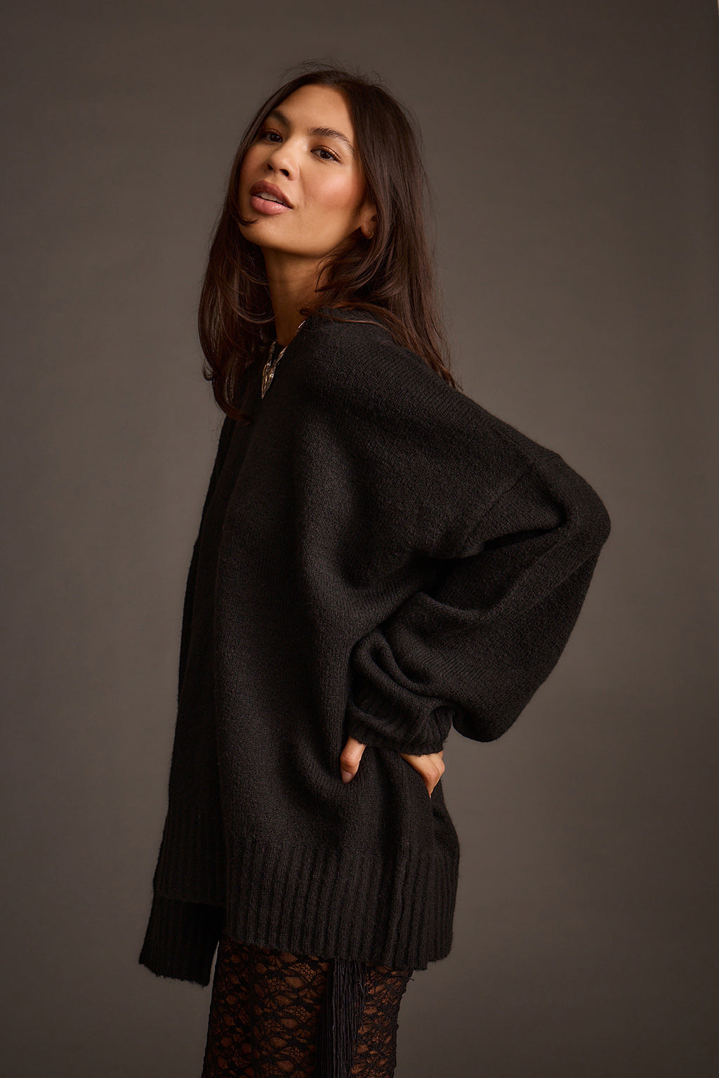 Side view of a black oversized sweater with balloon sleeves and a ribbed hem